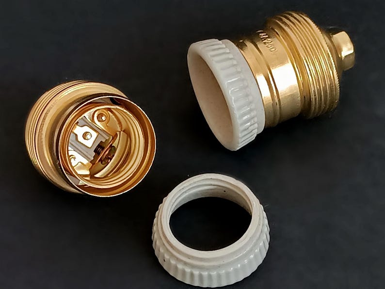 May include: Two gold-coloured light bulb sockets with white ceramic parts. The sockets are disassembled, showing the internal wiring and the ceramic parts.