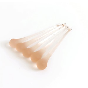 May include: Set of five clear glass stirring spoons with frosted pink tips. The spoons are arranged in a fan shape.