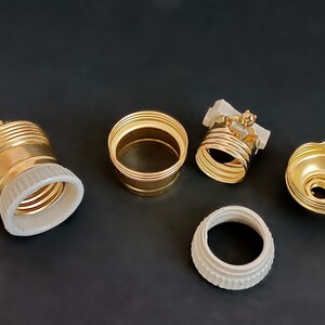 May include: Five gold-coloured light bulb sockets with white porcelain inserts. The sockets are in various stages of assembly.