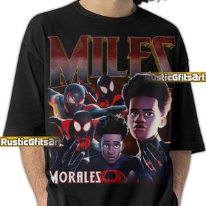 May include: Black t-shirt featuring a graphic of Miles Morales from the Spider-Man animated movie. The design includes the word "MILES" in a gradient font and "MORALES" below the image. The image has a comic book style.