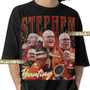 May include: Black t-shirt featuring a collage of images of a man wearing glasses and a red and orange shirt. The name "STEPHEN" is printed in a gold, vintage-style font above the images, and "Bunting" is printed below. A dartboard trophy is also visible.