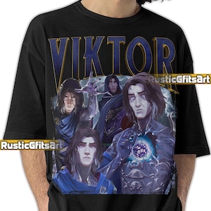 May include: Black t-shirt featuring a graphic of a character named Viktor. The design includes the name "VIKTOR" in gold lettering above a collage of Viktor's image. The shirt has the text "RusticGfitsArt" in the lower left and right corners.