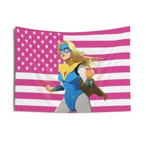 May include: A wall tapestry featuring a superheroine in a blue and yellow costume with a pink and white American flag background. The illustration depicts a blonde-haired character with a mask, cape, and clenched fists, radiating energy.