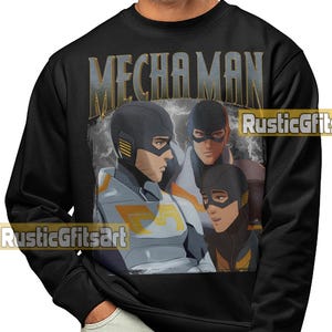 May include: Black sweatshirt with a graphic of three characters from the animated series "Mechaman." The characters are illustrated in a comic book style, wearing helmets and futuristic clothing. The word "MECHAMAN" is printed across the top.