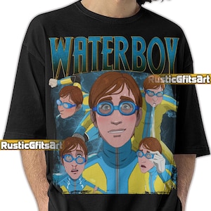 May include: Black t-shirt featuring a cartoon illustration of a person wearing blue goggles and a yellow and blue wetsuit. The word "WATERBOY" is printed in blue and gold. The shirt also has the text "RusticGiftsArt".