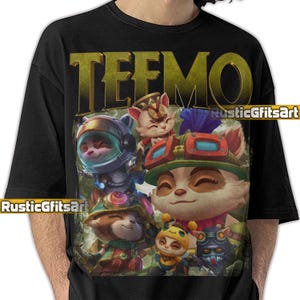 以下が含まれることがあります： 黒いTシャツ。カラフルな漫画のキャラクターのグラフィックと、金色の文字で「TEEMO」という文字が描かれています。キャラクターは様々な衣装を着ています。シャツには「RusticGfitsArt」という文字も白で書かれています。