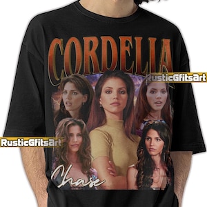 May include: Black t-shirt featuring a vintage-style graphic of a woman with the name "CORDELIA" in an orange and brown font. The graphic includes multiple images of the woman and the name "Chase" in a script font. The shirt has the "RusticGfitsArt" logo.