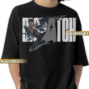 May include: Black t-shirt featuring a graphic of a female superhero with a mask and cape, with the word "BATCH" in large white letters. The shirt also has the text "RusticGiftsArt" in white.