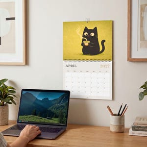 2027 black cat wall calendar featuring adorable Japanese-inspired cat illustrations for cat lovers and cozy home decor.
Cute black cat calendar 2027 with whimsical monthly artwork, perfect gift for cat moms, cat dads, and pet lovers.