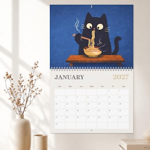 Japanese inspired wall calendar showcasing a playful black cat enjoying ramen, cherry blossoms, moon viewing and seasonal traditions.