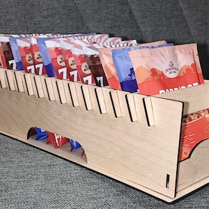 Może przedstawiać: Drewniany organizer z przegródkami na przekąski. Organizer ma oddzielny przedział na przechowywanie większych przedmiotów. Organizer jest wykonany z jasnobrązowego drewna i ma naturalne wykończenie.