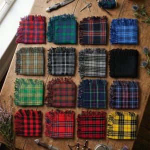 Peut inclure: Une collection de seize dessous de verre carrés en tartan de différentes couleurs, dont le rouge, le vert, le bleu et le noir, avec des bords frangés. Les dessous de verre sont disposés sur une surface en bois, présentant divers motifs écossais.