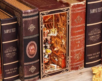 Puede incluir: Diorama en miniatura de una habitación dentro de un libro, con un interior detallado que incluye muebles, obras de arte y una lámpara de araña. El libro está rodeado de otros libros de estilo antiguo con el texto "SAMPLE TEXT" y elementos decorativos.