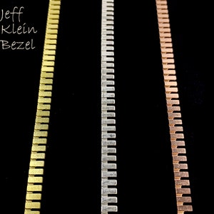 May include: Three metal chains, one gold, one silver, and one copper, are shown against a black background. The chains are made of small, rectangular links.