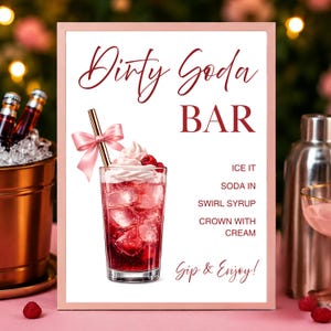 May include: A pink-framed sign with the words "Dirty Soda Bar" in elegant script. The sign features a detailed illustration of a cocktail with ice, red syrup, whipped cream, and raspberries. Instructions are listed below the illustration.
