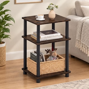 May include: A three-tier side table featuring dark brown wood-grain shelves supported by four matte black cylindrical metal legs. The square shelves provide open storage space, with the bottom level containing a woven light brown wicker basket.