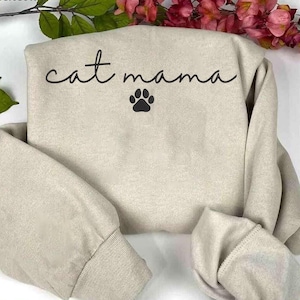 May include: A light beige sweatshirt with the text "cat mama" and a black paw print.