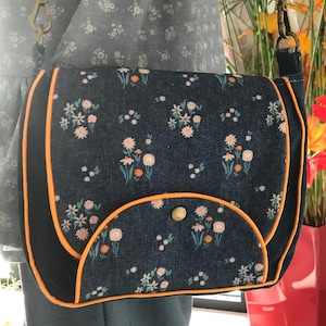 Besace en jeans fleuri recyclé. Anse réglable. Doublée en coton bleu. Poche intérieur zippée.