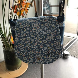 Besace en tissu recyclé jean et coton. 1 poche zippée intérieure et une extérieure (dos de la besace). Anse réglable