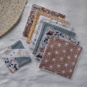 Op de afbeelding: Een verzameling vierkante stoffen onderzetters met verschillende patronen, waaronder bloemen-, geometrische en vlinderontwerpen. De onderzetters hebben een mix van kleuren zoals bruin, wit, geel en groen. De onderzetters zijn gerangschikt op een wit oppervlak.