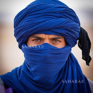 May include: A person wearing a vibrant blue turban and face covering. The fabric is wrapped around the head and face, with the text "SAHARA 45" visible. A black cloth hangs from the turban.