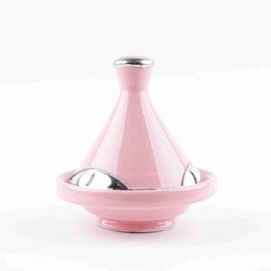 May include: A pink ceramic tagine pot with a conical lid and a silver-colored handle. The base has a circular design with silver accents. The tagine is a traditional Moroccan cooking vessel.