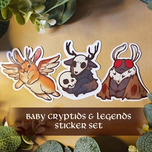 May include: A sticker set with three fantasy creature designs. The stickers depict a winged rabbit, a deer-like figure with a skull, and a moth with red eyes. The text "BABY CRYPTIDS & LEGENDS STICKER SET" is shown.