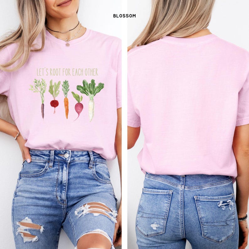 May include: A pink t-shirt with the text "Let's root for each other" and a graphic of five vegetables. The vegetables are a carrot, a radish, a beet, a turnip, and a sprig of dill.