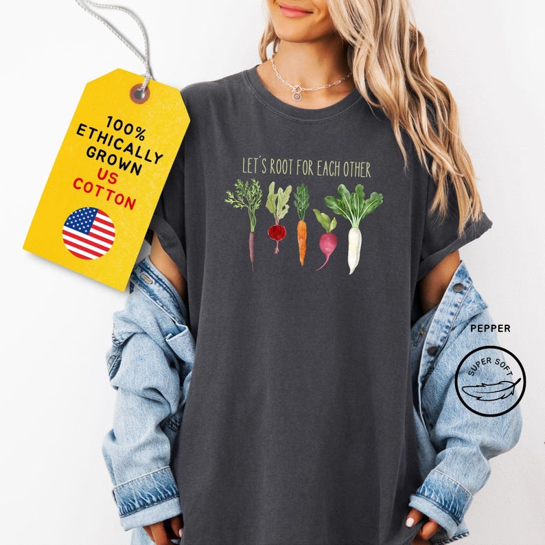 A dark gray t-shirt with the text 'Let's root for each other' and a graphic of five different vegetables. The vegetables are a carrot, a radish, a beet, a turnip, and a white radish.
