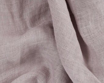 May include: A close-up of a soft, light purple fabric with a textured weave. The fabric is wrinkled and folded, showing its drape and texture.