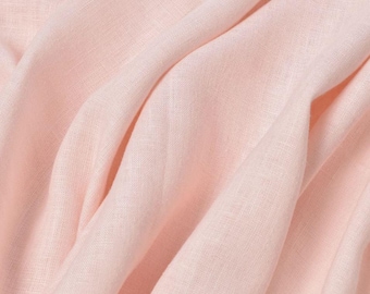 May include: A close-up of a soft, pale pink linen fabric with a subtle texture. The fabric is folded and draped, showcasing its drape and flow.