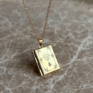 May include: Gold chain necklace with a gold locket pendant. The locket is engraved with the words "In My Villain Era".