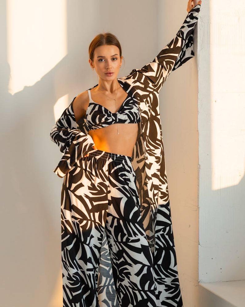 Puede incluir: Un conjunto a juego con estampado en blanco y negro que consta de un top de sujetador, pantalones de cintura alta y una chaqueta de manga larga. El conjunto tiene un dise&ntilde;o abstracto y audaz. La modelo lleva un delicado collar.