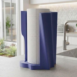 Può includere: Un portarotolo verticale con una struttura geometrica angolare blu scuro che avvolge un rotolo standard di carta assorbente bianca. Il supporto presenta una base solida e un design strutturato e moderno che mantiene il rotolo in verticale.
