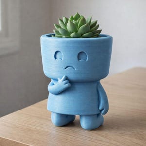 May include: A light blue, anthropomorphic planter with a thoughtful expression, holding its chin. The planter has a cylindrical head and body, with a small succulent plant in the head. The planter is on a wooden surface.
