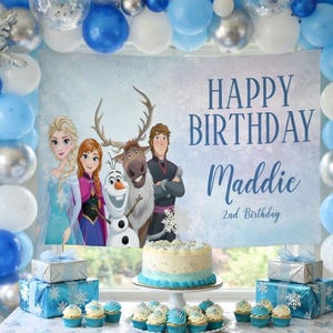 May include: A birthday party scene with a banner that reads "Happy Birthday Maddie 2nd Birthday." The scene includes blue, silver, and white balloons, a cake, cupcakes, and wrapped gifts. The banner features characters from the movie Frozen.