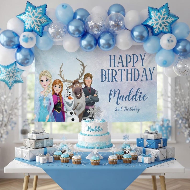 May include: A festive birthday party scene with a blue and white theme. A banner reads "Happy Birthday Maddie" with the characters from the movie Frozen. A cake, cupcakes, and wrapped gifts are on a table decorated with balloons and snowflake accents.