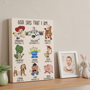 May include: A canvas print featuring cartoon characters with the text "GOD SAYS THAT I AM..." and various affirmations like "EMPOWERED" and "TREASURED." The print includes a photo frame with a baby picture and a white bunny toy.