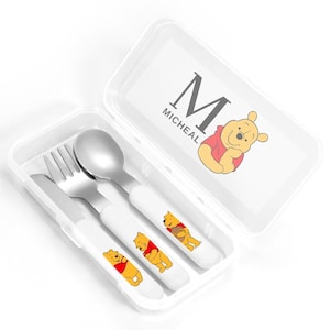 May include: A Winnie the Pooh themed cutlery set with a fork, knife, and spoon. The set comes in a clear plastic case with a Winnie the Pooh character and the name "Micheal" printed on the lid.