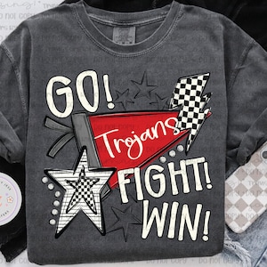 May include: Dark gray t-shirt with the words "GO! FIGHT! WIN!" and "Trojans" in white and red. The design includes stars, a checkered lightning bolt, and a star with a checkered pattern.