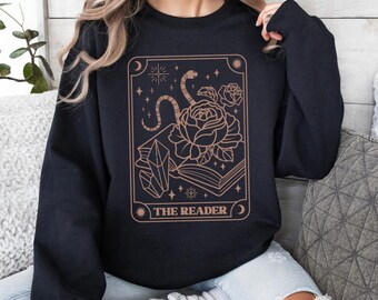May include: Black sweatshirt with a tarot card design featuring a snake, a rose, and a book. The card reads "The Reader".