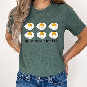 May include: A green t-shirt with a white background featuring a graphic of deviled eggs and the text "YOU KNOW WHY I'M HERE."