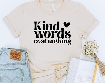May include: A beige t-shirt with black text that reads "Kind words cost nothing" and a small black heart.