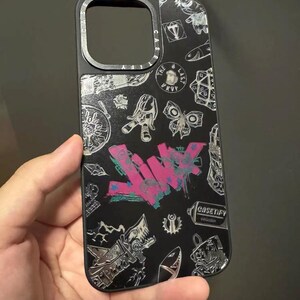 Peut inclure: Coque de t&eacute;l&eacute;phone noire avec un design graphique argent&eacute; et blanc mettant en vedette le mot "LWYK" en graffiti rose et bleu et d'autres motifs vari&eacute;s. La coque a un anneau de cam&eacute;ra sur&eacute;lev&eacute; et le texte "CASETIFY" imprim&eacute; en bas &agrave; droite.