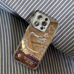 May include: A silver mirror phone case with a Hello Kitty design. The case has a pink heart and stars. The text on the case reads "Hello Kitty. Way you become your own ann, without refying on anyone's light."