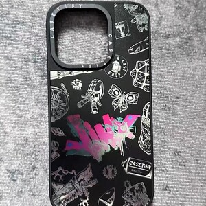 Peut inclure: Coque de t&eacute;l&eacute;phone noire avec un design graphique argent&eacute; et rose repr&eacute;sentant un papillon, un cr&acirc;ne, une bombe de peinture et le texte "CASETIFY".