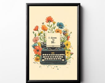 May include: A framed art print featuring a vintage typewriter with a paper that reads "I choose to BE." The typewriter is surrounded by colorful flowers in shades of orange, yellow, pink, and blue. The artwork has a cream-colored background.