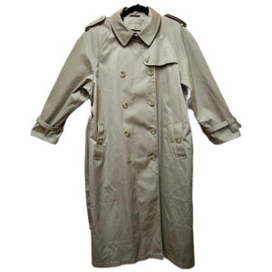 May include: A tan trench coat with a double-breasted design. The coat features a notched collar, shoulder epaulets, and a belt. The sleeves have adjustable cuffs. The coat is hanging on a black hanger.