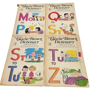 Puede incluir: Cuatro ejemplares antiguos de "The Charlie Brown Dictionary" de Charles M. Schulz. Los libros presentan ilustraciones coloridas de los personajes de Peanuts y letras grandes. Las portadas están desgastadas.