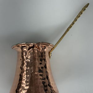 Peut inclure: Une cafetière turque en cuivre avec une longue poignée en laiton texturé. La cafetière a une texture martelée et un bord évasé. La poignée est fixée avec un petit raccord en laiton. Conçu pour infuser le café turc.